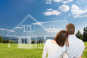 Homeowners with arms areound each other looking out over a plot of land where a line drawing of a home designed by a custom home builder of Monmouth County is