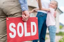 SOLD sign in the hand of a Seaside Park real estate agent handing keys over to new owner.